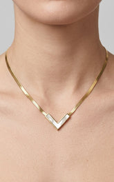 Gold necklace with a V-shaped pendant on a neutral background