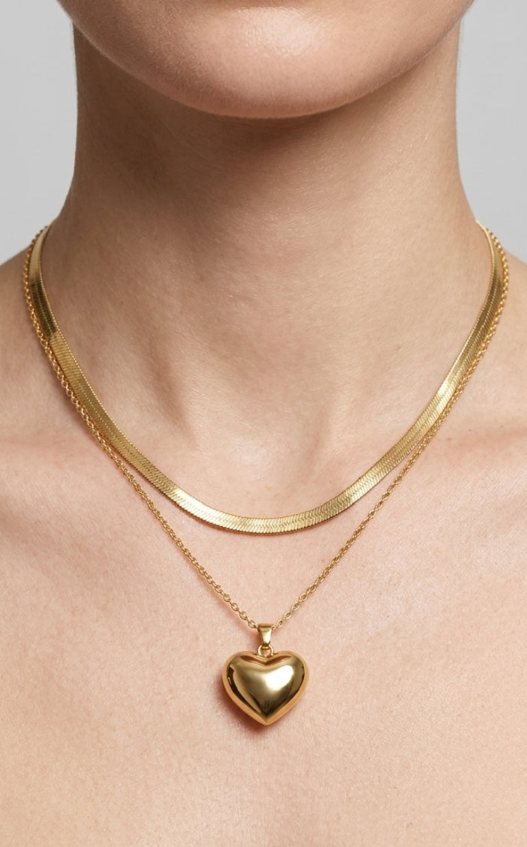 Gold necklace with a heart-shaped pendant on a neutral background
