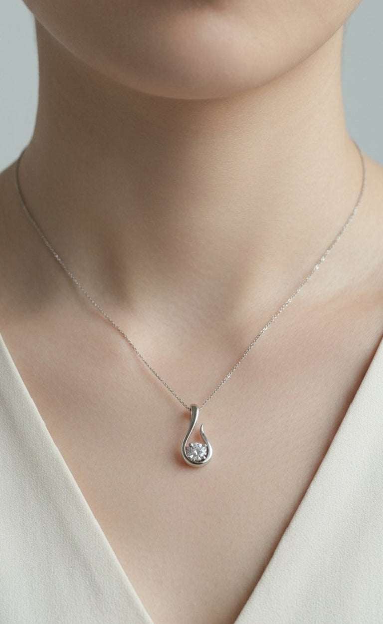 Silver teardrop pendant necklace on a model wearing a white top