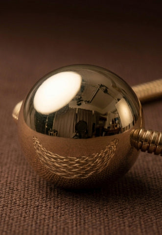 Gold spherical object with reflective surface on a brown textured background