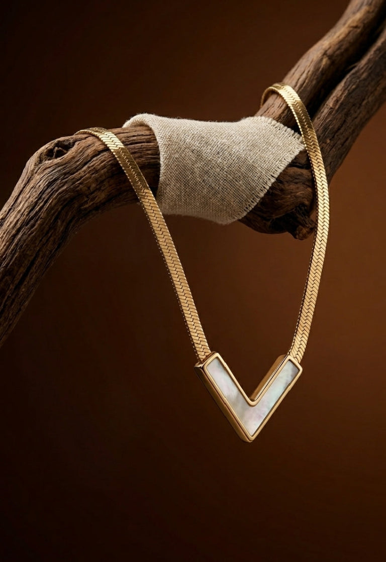 Gold necklace with a white stone on a brown background