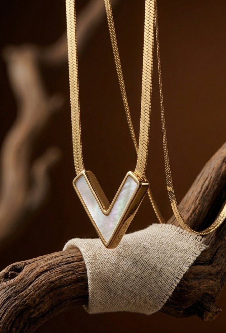 Gold necklace with a V-shaped pendant on a wooden branch