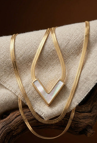 Gold necklace with a white pendant on a textured surface