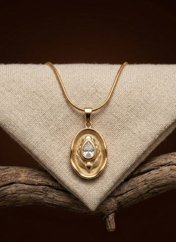Gold necklace with a pendant on a textured surface
