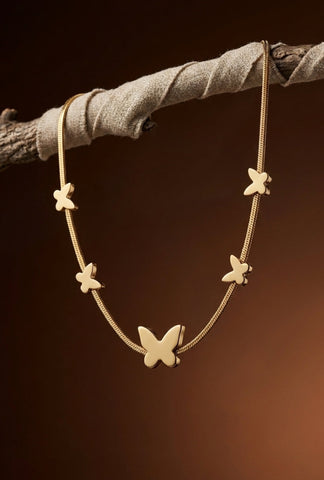Gold butterfly necklace on a dark brown background