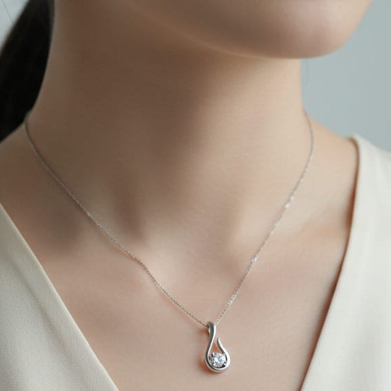 Mannequin wearing a delicate necklace with a clear pendant against a neutral background
