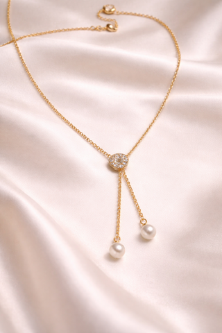 Gold necklace with pearl pendants on a satin surface
