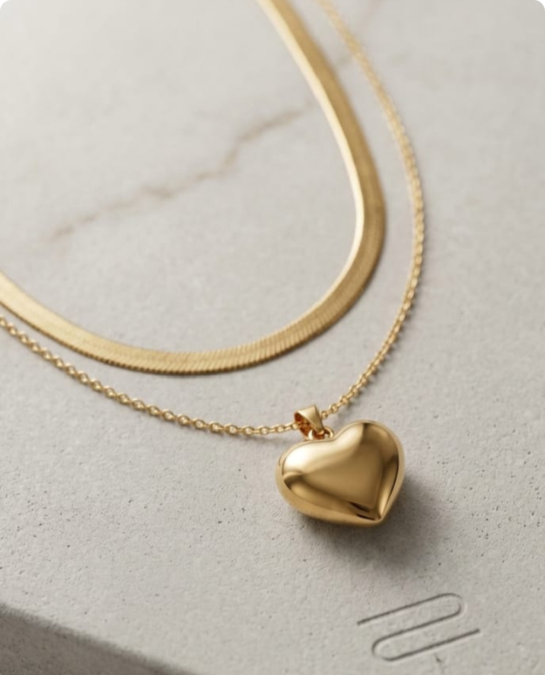 Gold heart-shaped pendant necklace on a light gray surface