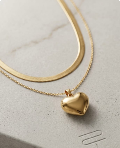 Gold heart-shaped pendant necklace on a light gray surface